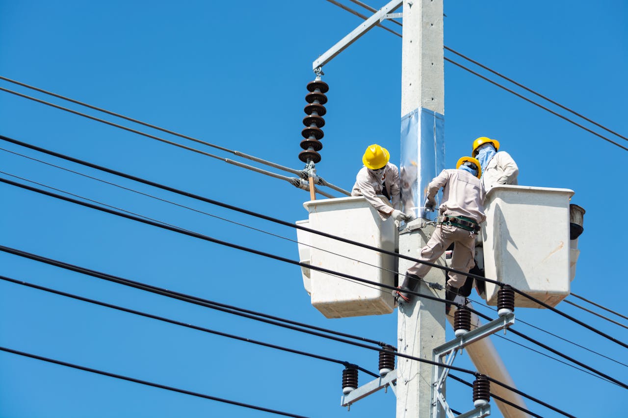 Three energy field service workers on a power line