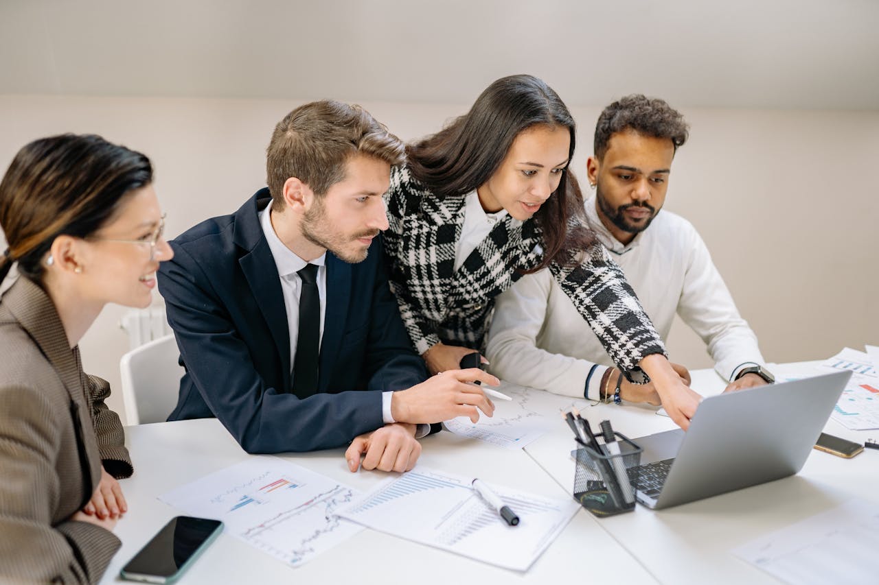 Men and women reviewing business data on a laptop computer.