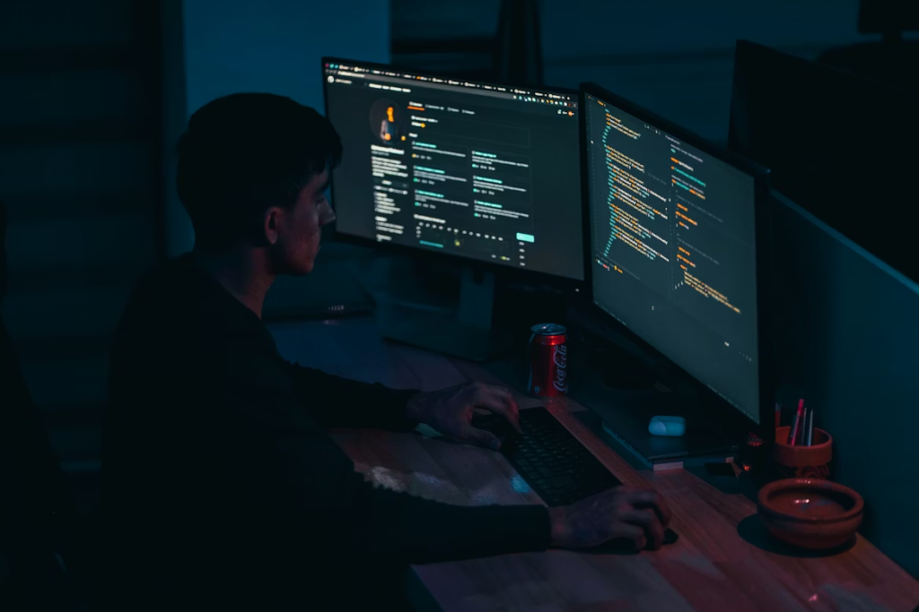 Man writing code in front of computer screens
